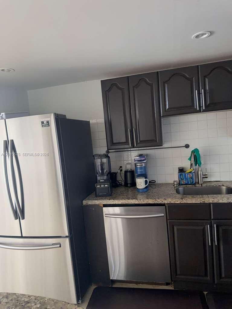 A kitchen features dark wood cabinets, stainless steel appliances, and a granite countertop — 13499 Biscayne Blvd # 906, North Miami FL 33181, NORTH MIAMI, FL