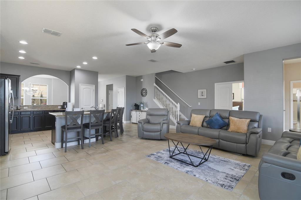 An open-concept living room and kitchen featuring gray walls, tile flooring, and a staircase — 4115 OAKTREE DRIVE, DAVENPORT, FL