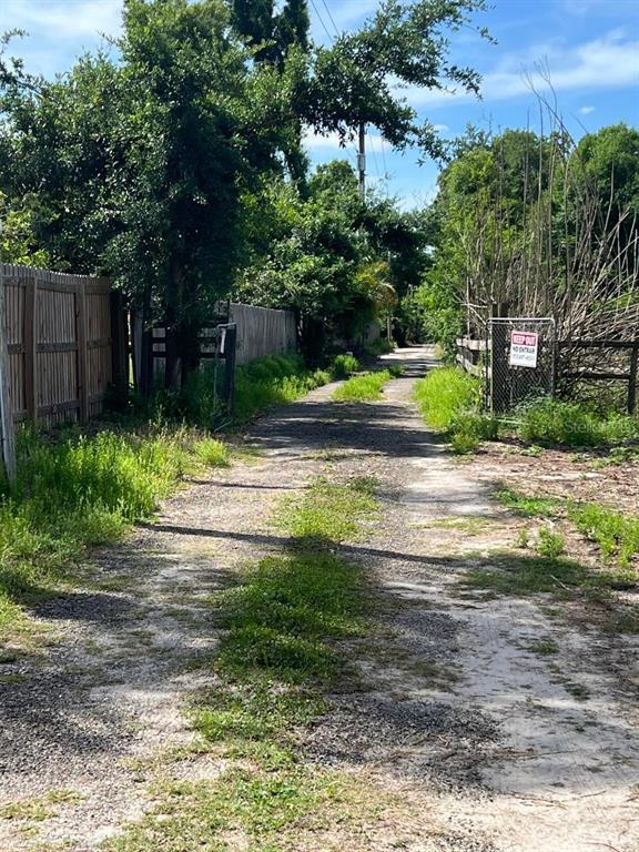 A dirt path leads between a wooden fence and a chain-link fence toward trees — 15617 CASEY ROAD, TAMPA, FL