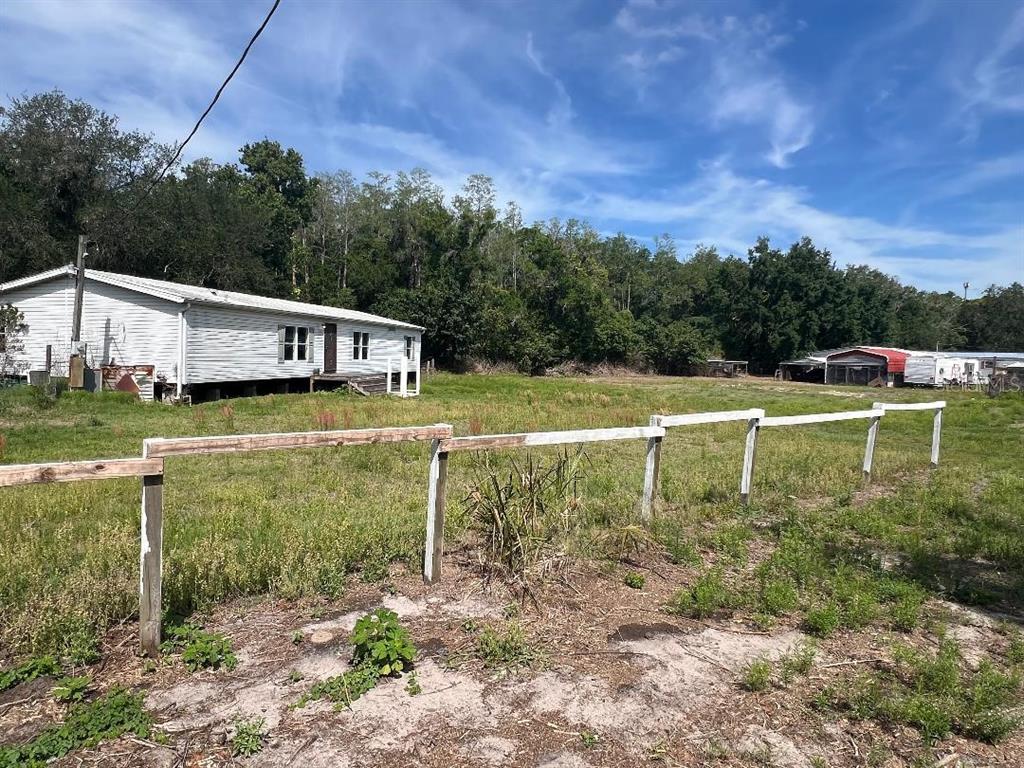 A white mobile home sits on a grassy lot behind a wooden post-and-rail fence — 15617 CASEY ROAD, TAMPA, FL