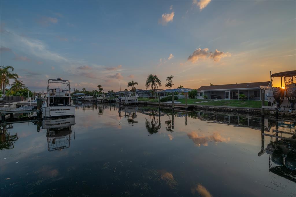 A canal view at sunset featuring a boat docked in front of a residential home — 6322 COTTONWOOD LANE, APOLLO BEACH, FL