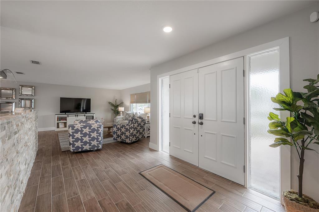 An entryway with tile flooring leads into a living room featuring patterned armchairs — 6322 COTTONWOOD LANE, APOLLO BEACH, FL