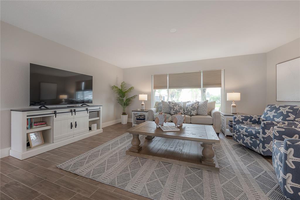 A living room features a television console, a sofa, patterned armchairs, and a coffee table — 6322 COTTONWOOD LANE, APOLLO BEACH, FL
