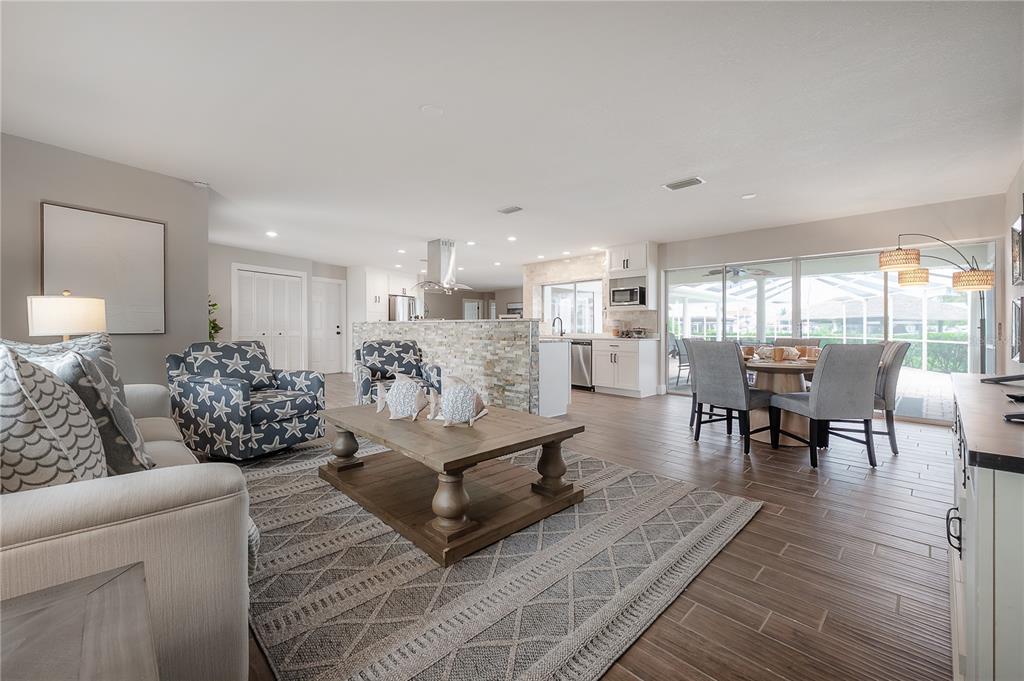 An open-concept living and dining area features tile flooring, a stone-accented kitchen island, and furniture — 6322 COTTONWOOD LANE, APOLLO BEACH, FL