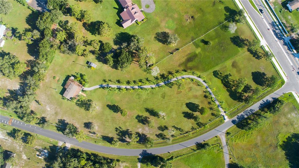 An aerial view shows a house with a long, curved driveway lined with palm trees — 3440 BOGGY CREEK ROAD, KISSIMMEE, FL
