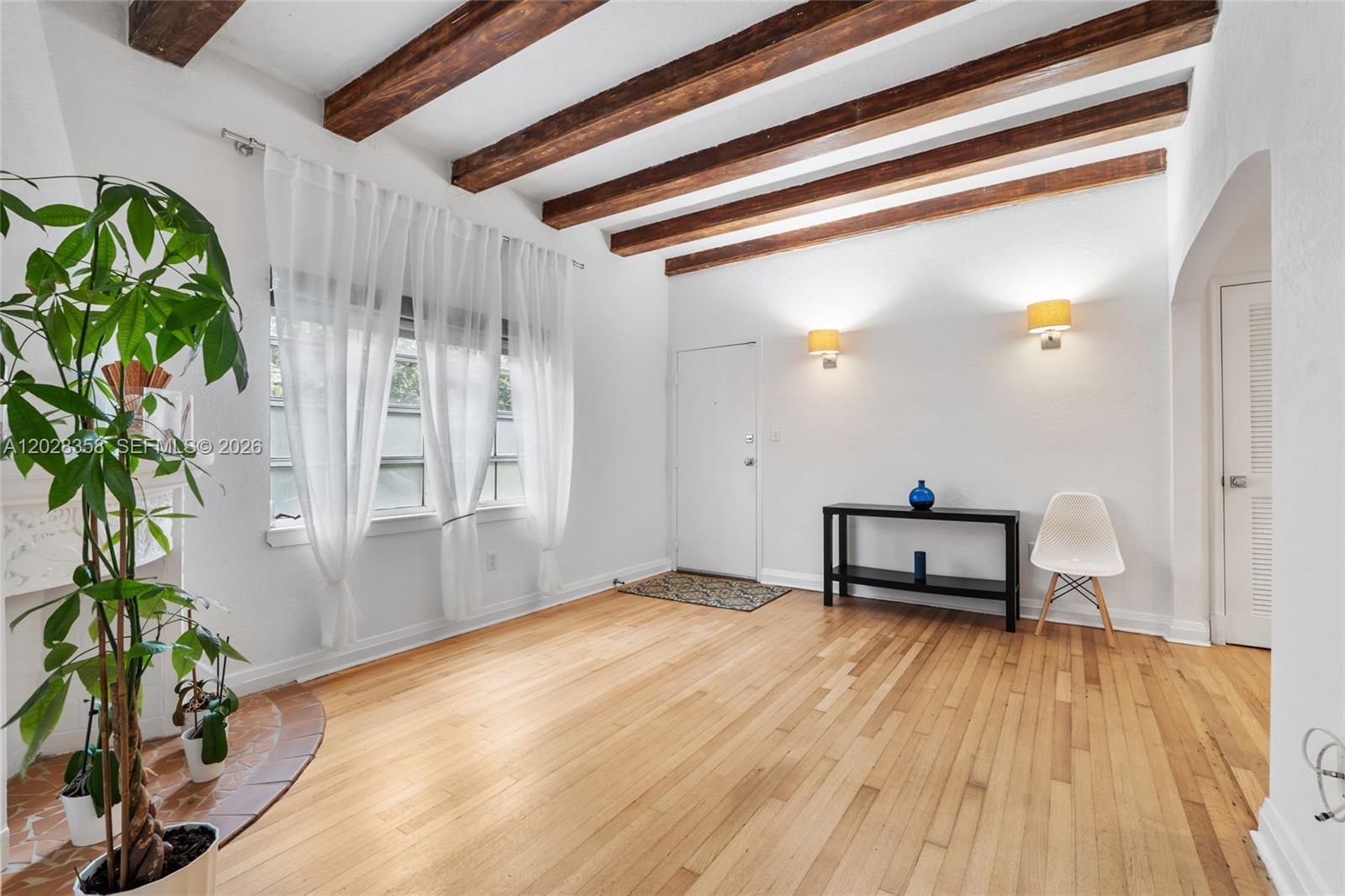 A living room features hardwood floors, exposed wood ceiling beams, and a white front door — 1605 Euclid Ave # B1, Miami Beach FL 33139, MIAMI BEACH, FL