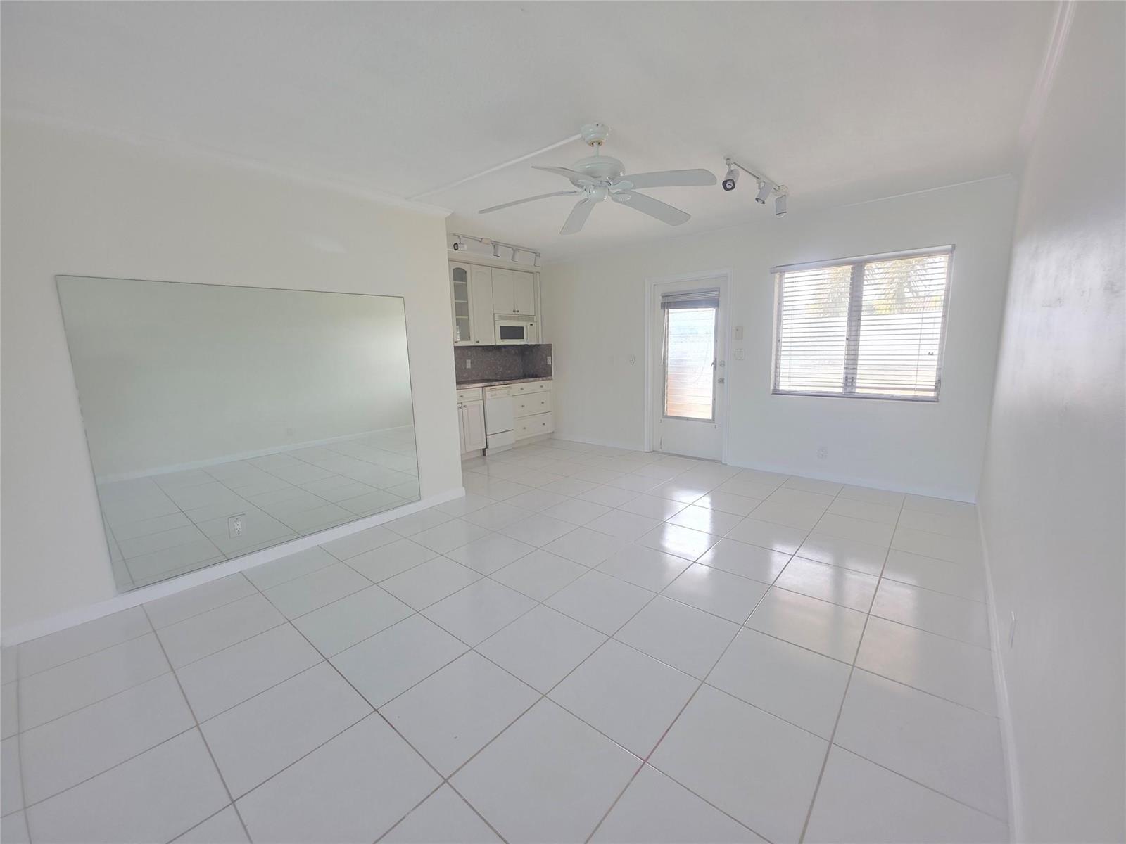 A bright room features white tile flooring, a large wall mirror, and a small kitchenette — 2131 NE 42nd Court # 209e, Lighthouse Point FL 33064, LIGHTHOUSE POINT, FL