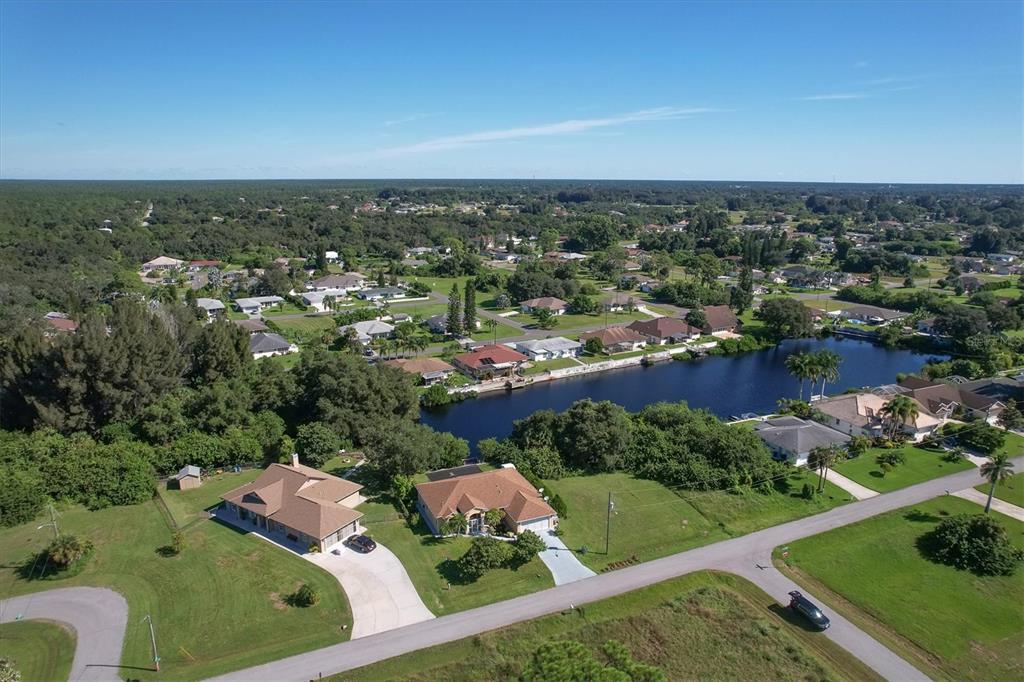 An aerial view shows suburban houses with green lawns situated along a narrow canal — 12004 SARTO LANE, NORTH PORT, FL