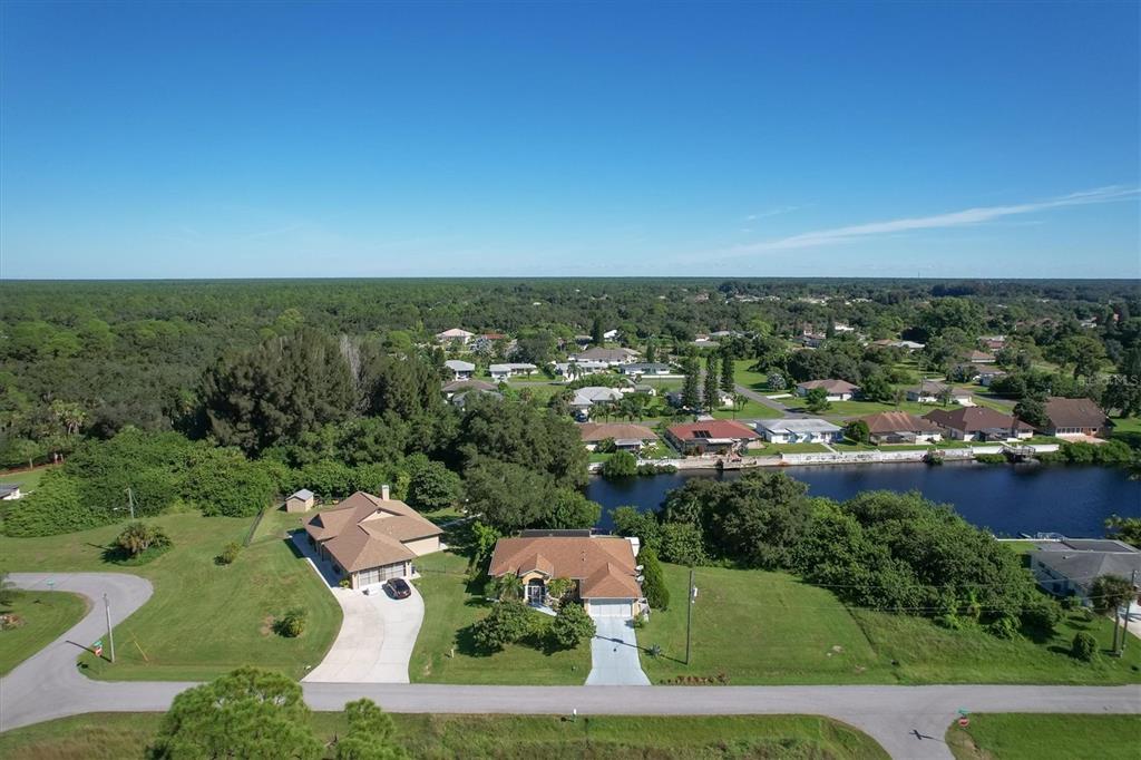An aerial view shows two houses with driveways situated along a canal in a neighborhood — 12004 SARTO LANE, NORTH PORT, FL