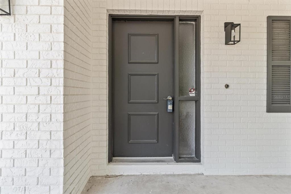 A dark gray front door with three panels sits beside a vertical sidelight window — 1255 S ESTATE POINT, INVERNESS, FL