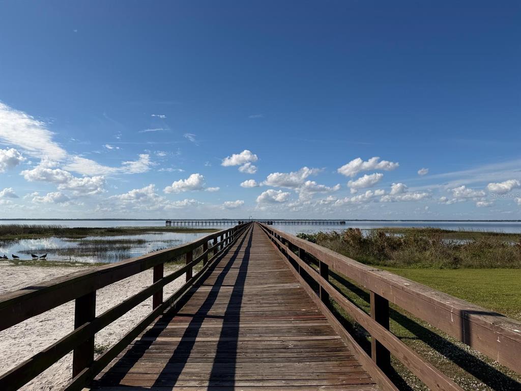 A long wooden boardwalk extends over a body of water under a blue sky — 405 BOUGAINVILLE DRIVE, INDIAN LAKE ESTATES, FL