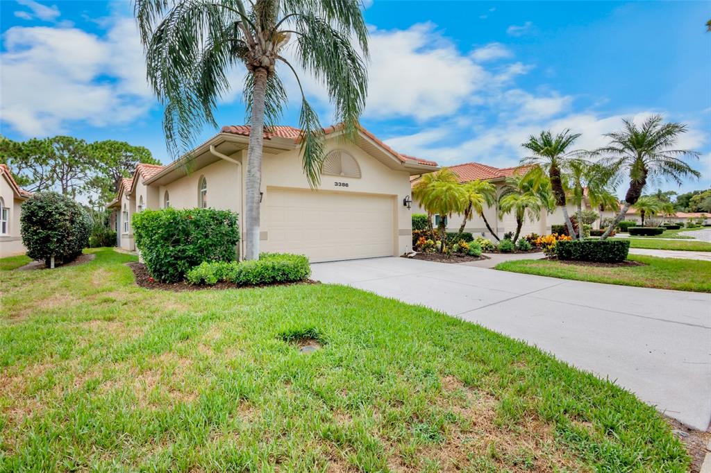 A beige single-story house with a two-car garage and palm trees in the front yard — 3386 CHELMSFORD COURT UNIT 7, SARASOTA, FL