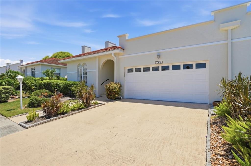 A single-story house with a white stucco exterior, a two-car garage, and a tiled roof — 4904 61ST AVENUE TERRACE W, BRADENTON, FL