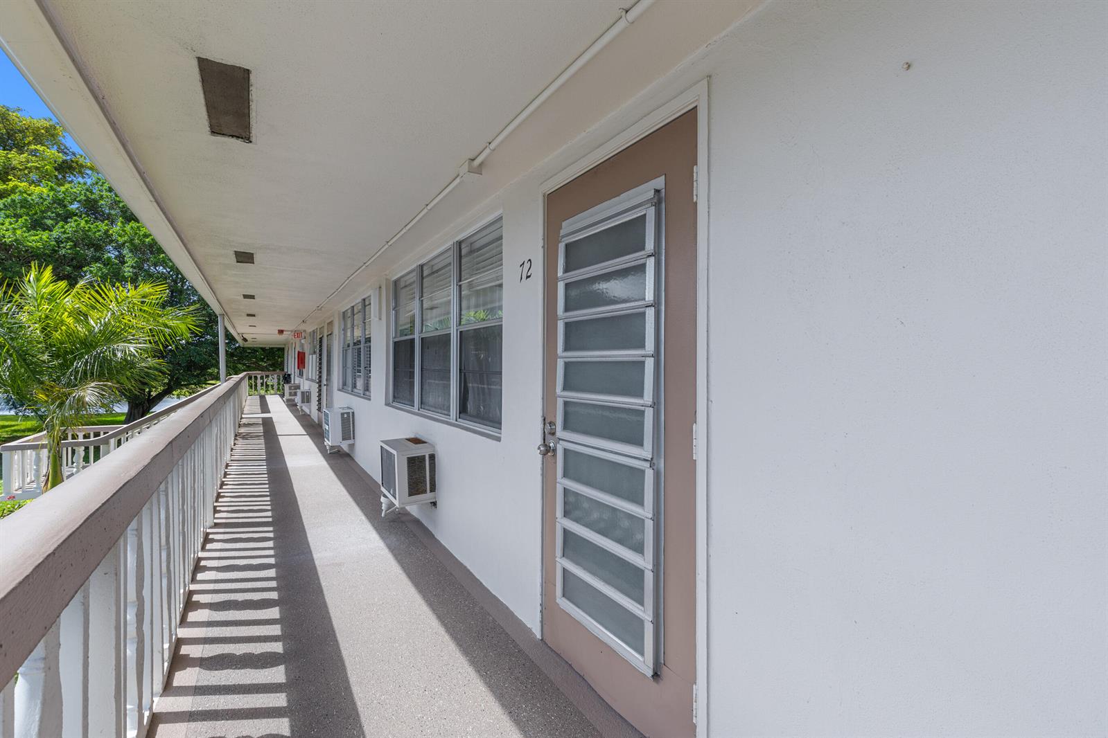An outdoor walkway leads past a door numbered 12 and several windows on a building — 72 Ashby B, Deerfield Beach FL 33442, DEERFIELD BEACH, FL