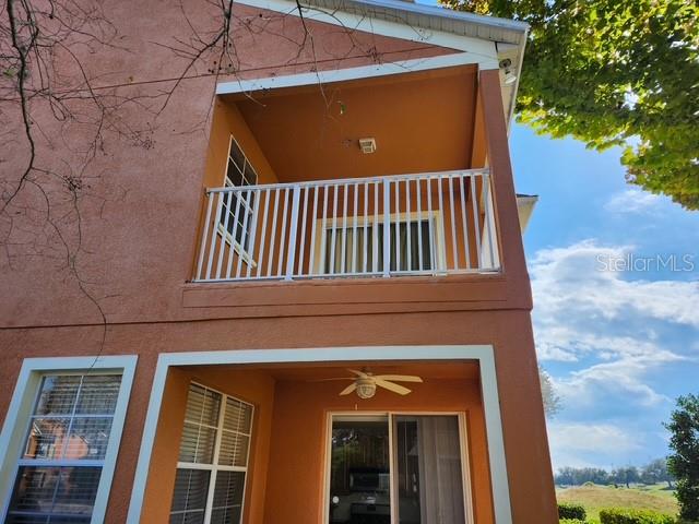 A two-story building exterior features a second-floor balcony with white railings above a patio — 834 ASSEMBLY CT, REUNION, FL