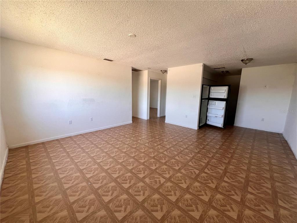 An empty room features patterned vinyl flooring, white walls, and a refrigerator in the corner — 3847 JANEEN CIRCLE, MULBERRY, FL