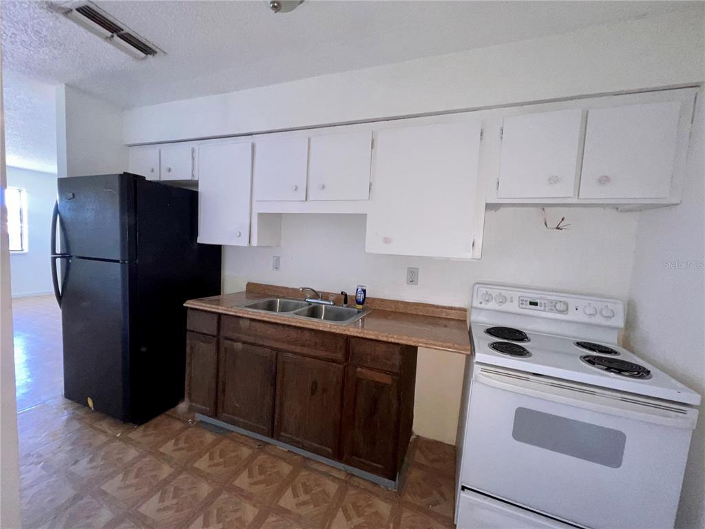 A kitchen features white upper cabinets, dark wood lower cabinets, a black refrigerator, and white stove — 3847 JANEEN CIRCLE, MULBERRY, FL