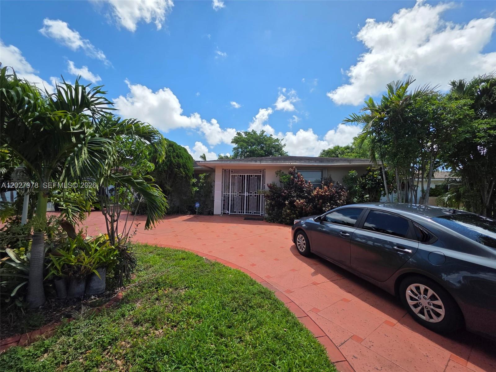 A single-story house with a red paved driveway and a metal security gate entrance — 16825 NW 74th Ave, Hialeah FL 33015, HIALEAH, FL