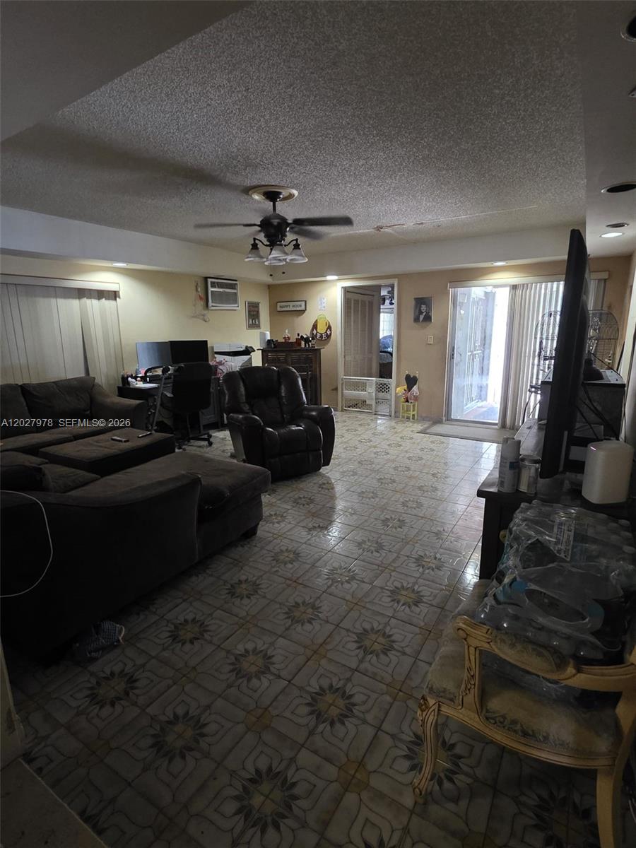 A living room features a dark sectional sofa, a recliner, tiled floors, and a ceiling fan — 16825 NW 74th Ave, Hialeah FL 33015, HIALEAH, FL