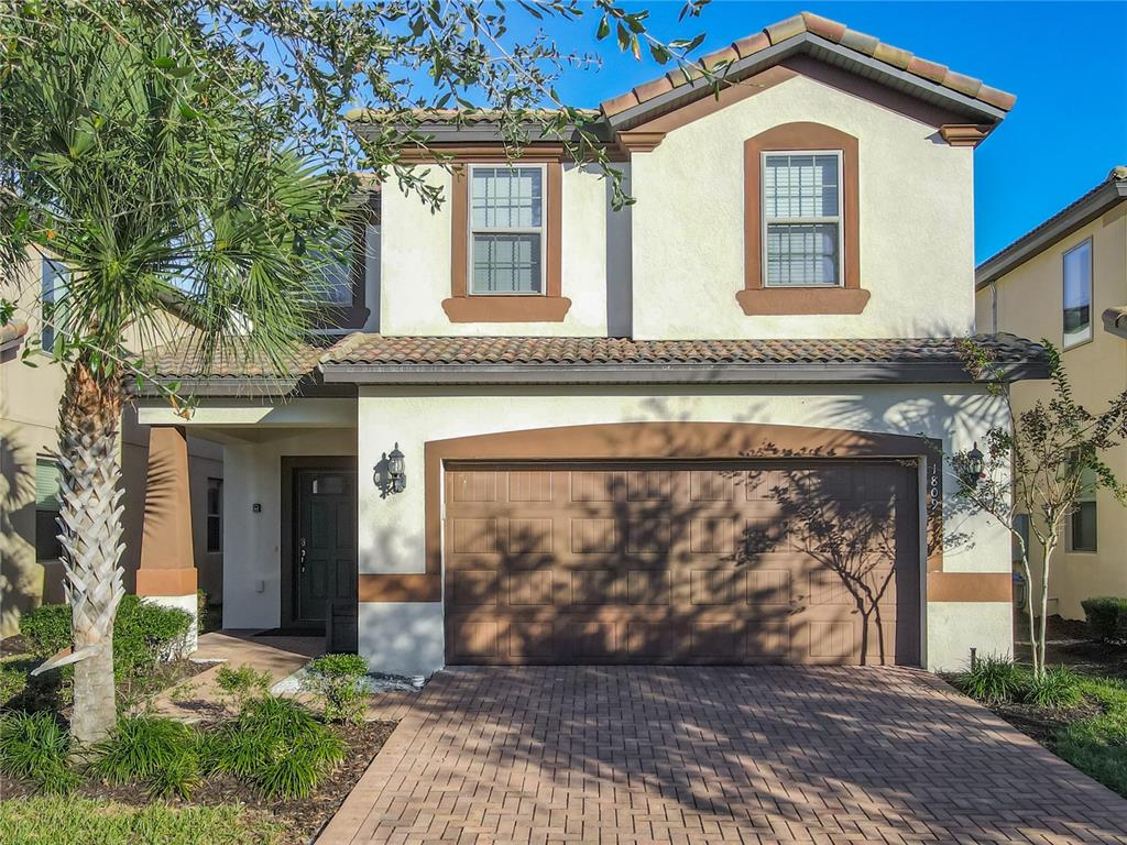 A two-story house with a brown garage door, stucco exterior, and a brick paver driveway — 1809 NICE COURT, KISSIMMEE, FL