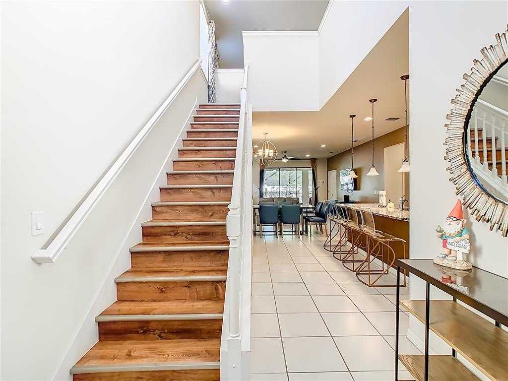 A staircase with wood treads leads to an open-concept living area with tile flooring — 1809 NICE COURT, KISSIMMEE, FL