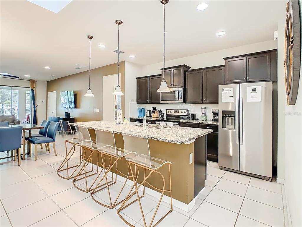 A kitchen with dark cabinets, granite countertops, a breakfast bar, and stainless steel appliances — 1809 NICE COURT, KISSIMMEE, FL