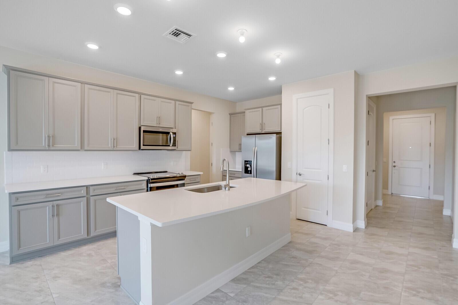 A kitchen with gray cabinets, white countertops, a center island, and stainless steel appliances — 8656 Escue Street, Lake Worth FL 33467, LAKE WORTH, FL