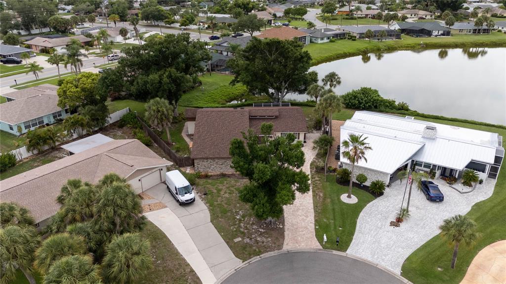 An aerial view shows three suburban houses with driveways, trees, and a nearby lake — 1141 SLEEPY HOLLOW COURT, VENICE, FL
