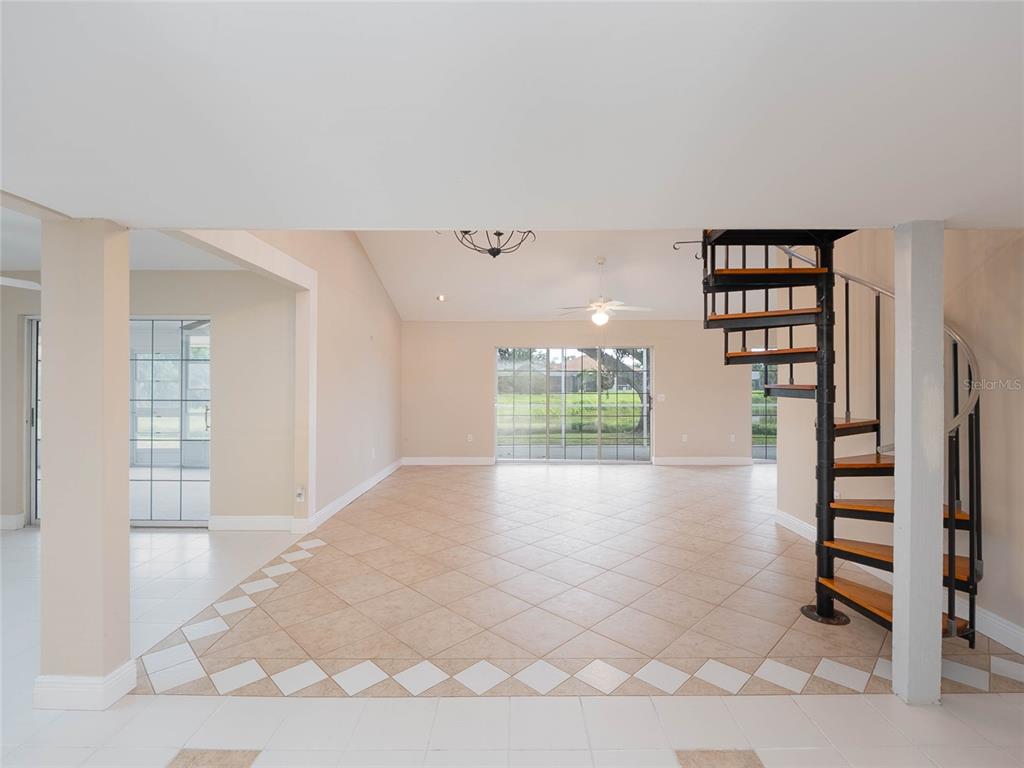 An open living area features a spiral staircase, tile flooring, and sliding glass doors — 1141 SLEEPY HOLLOW COURT, VENICE, FL