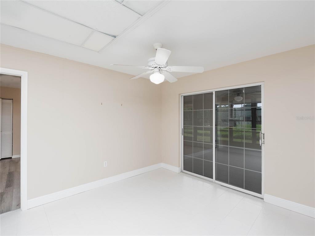 A room with white tile flooring, a ceiling fan, and sliding glass doors to a patio — 1141 SLEEPY HOLLOW COURT, VENICE, FL