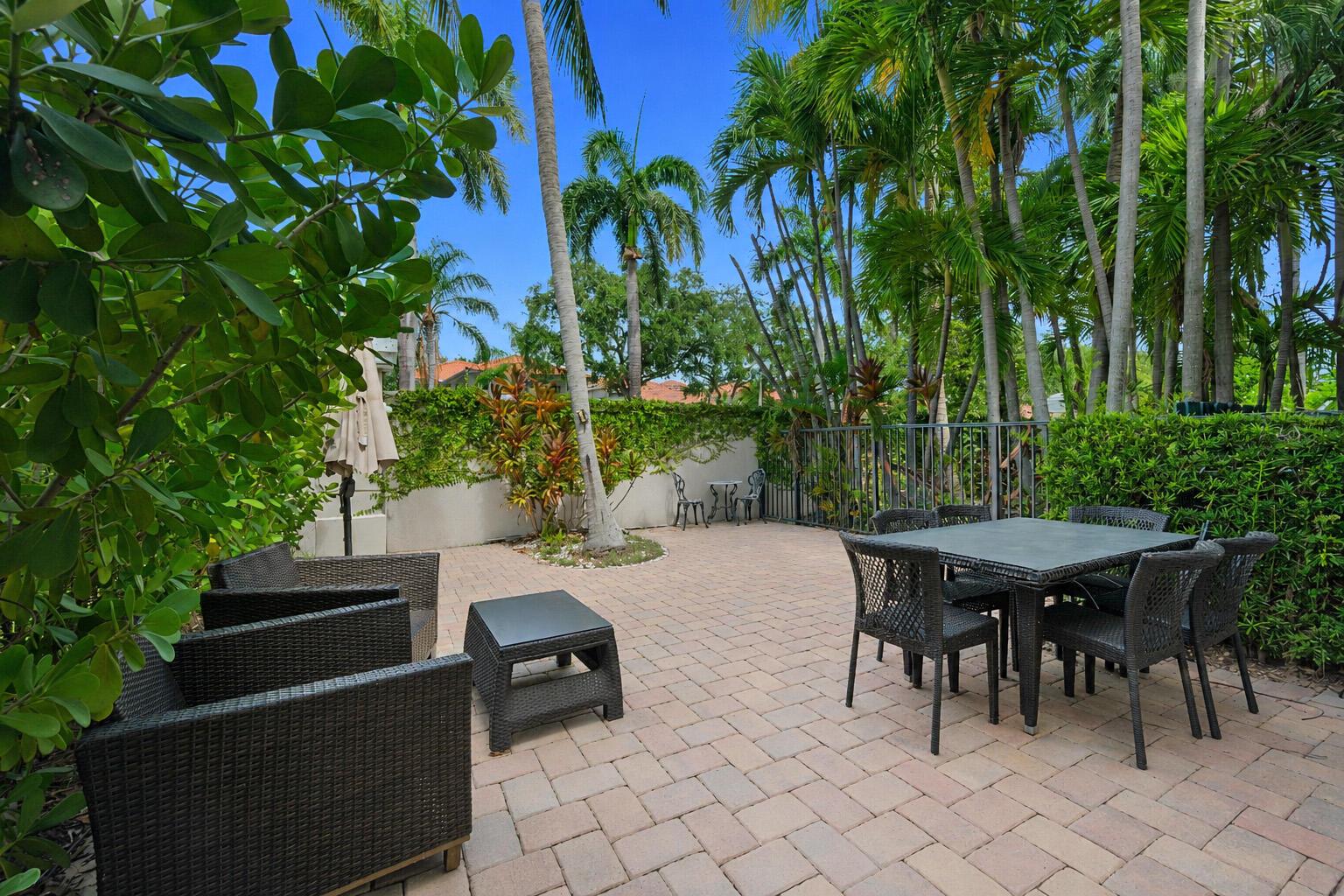 A paved outdoor patio features wicker furniture, a dining set, and lush tropical landscaping — 1384 Harbor View W, Hollywood FL 33019, HOLLYWOOD, FL