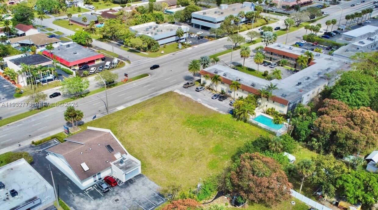 An aerial view shows a vacant grassy lot situated between a commercial building and apartments — 6200 W Atlantic Blvd, Margate FL 33063, MARGATE, FL