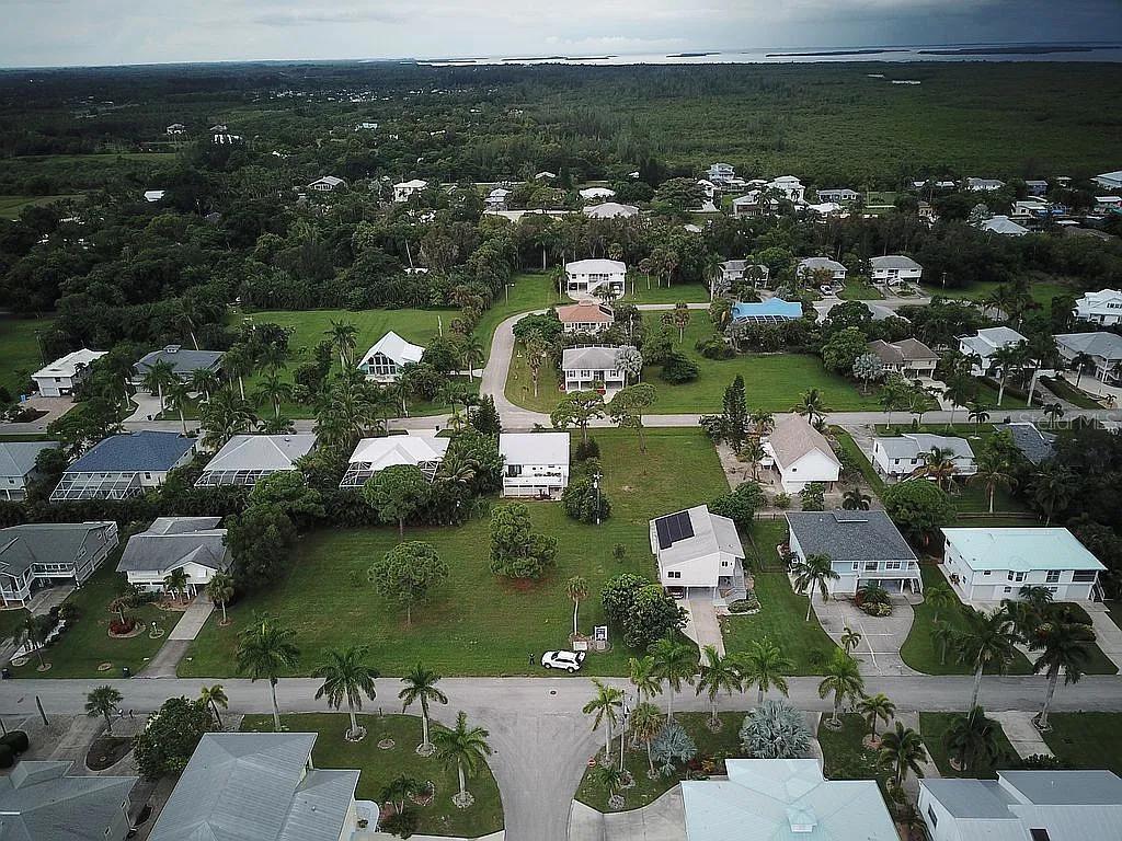 An aerial view shows a residential neighborhood with houses, palm trees, and green lawns — 7883 BREAKWATER COURT, BOKEELIA, FL