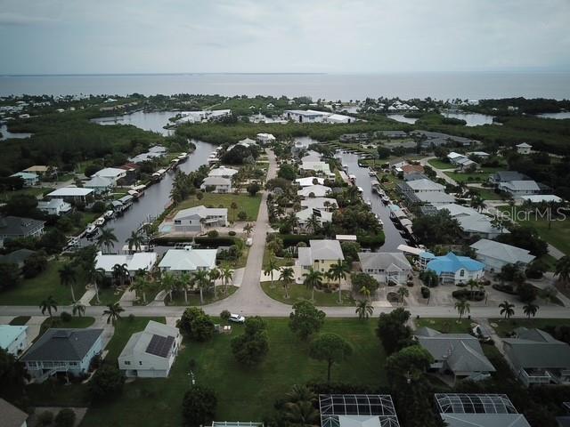 An aerial view shows a residential neighborhood with houses situated along canals near the water — 7883 BREAKWATER COURT, BOKEELIA, FL