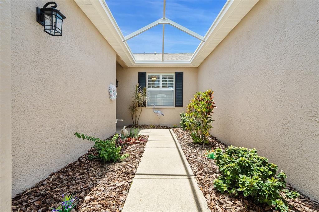 A concrete walkway leads to a house entrance under a screened-in roof enclosure — 7307 CLEOPATRA DRIVE, LAND O LAKES, FL