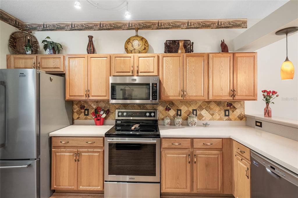 A kitchen with oak cabinets, stainless steel appliances, and a tiled backsplash — 7307 CLEOPATRA DRIVE, LAND O LAKES, FL