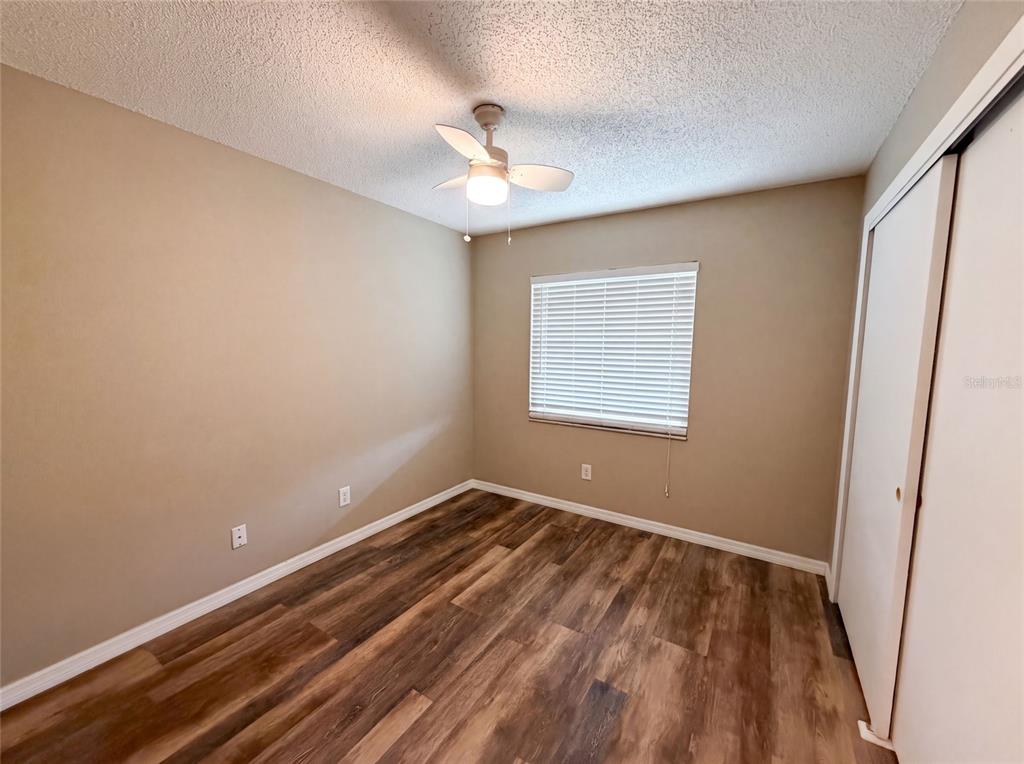 An empty bedroom features tan walls, wood-look flooring, a ceiling fan, and a sliding closet — 1393 SAN DIEGO COURT, WINTER SPRINGS, FL