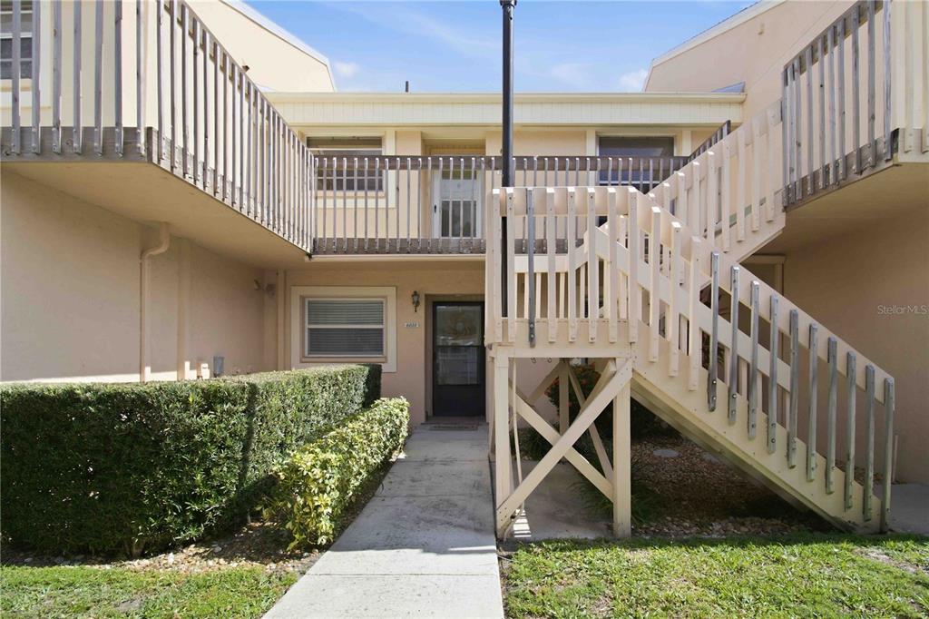 A two-story residential building features a concrete walkway leading to a ground-level entrance and stairs — 6032 7TH AVENUE W UNIT 6032, BRADENTON, FL