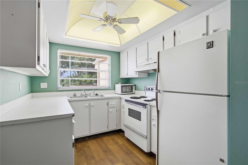 A kitchen features white cabinets, white appliances, a double sink, and light green walls — 6032 7TH AVENUE W UNIT 6032, BRADENTON, FL