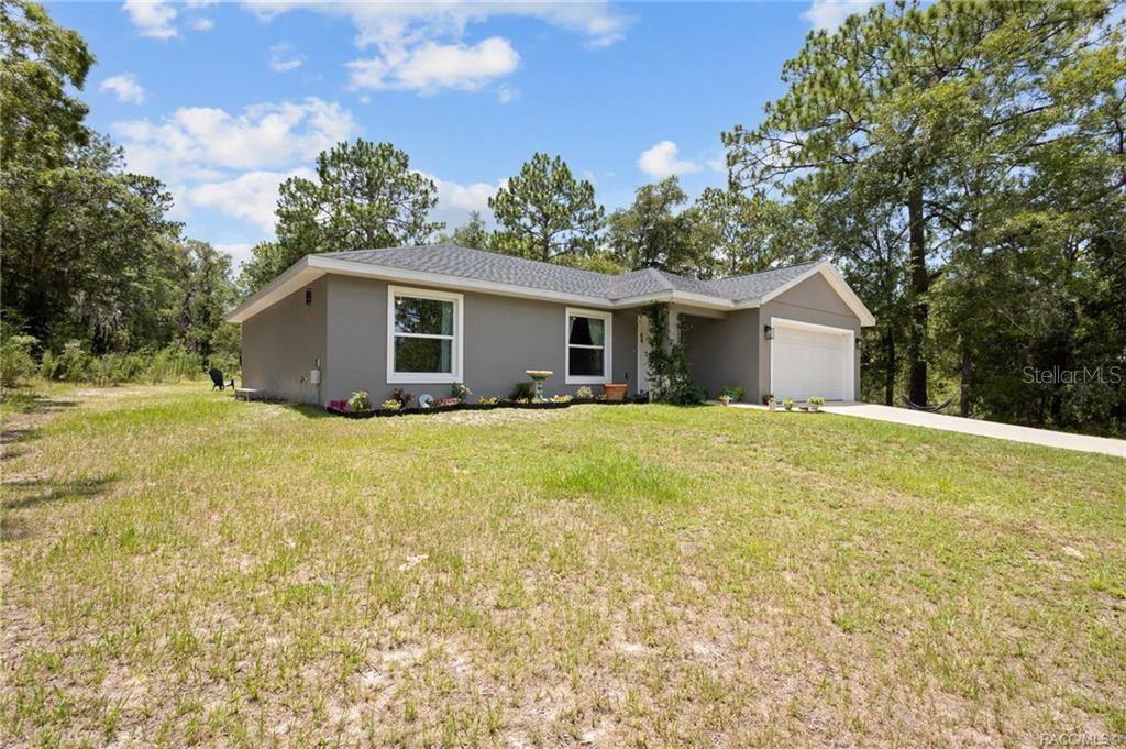 A single-story gray house with a white garage door sits on a grassy lot — 23092 NW SKYLARK STREET, DUNNELLON, FL