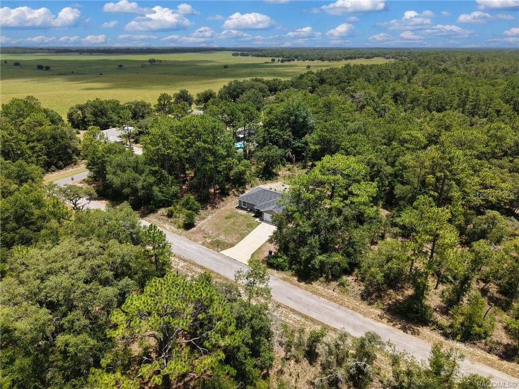 An aerial view shows a single-story house with a driveway surrounded by trees and fields — 23092 NW SKYLARK STREET, DUNNELLON, FL