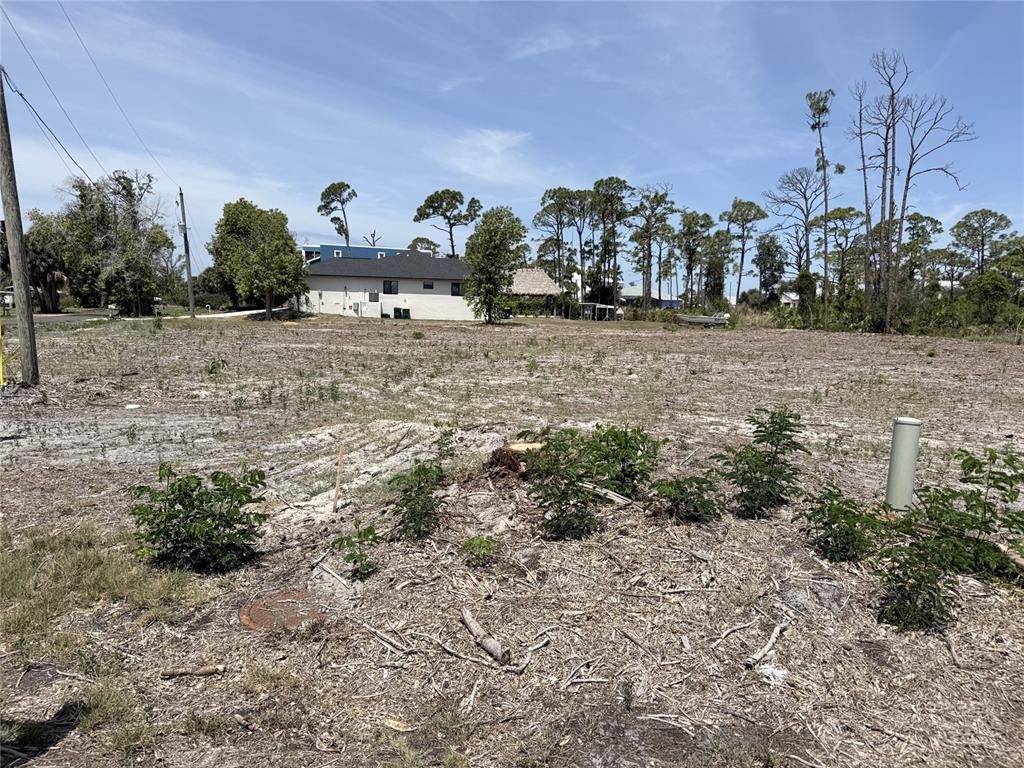 A vacant, cleared lot with sparse vegetation and a house visible in the background — 1890 VIRGINIA AVENUE, ENGLEWOOD, FL