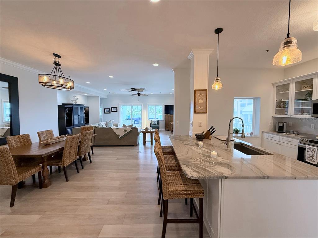 An open-concept kitchen and dining area features a large stone island and wood flooring — 423 S ATLANTIC AVENUE UNIT 102, NEW SMYRNA BEACH, FL