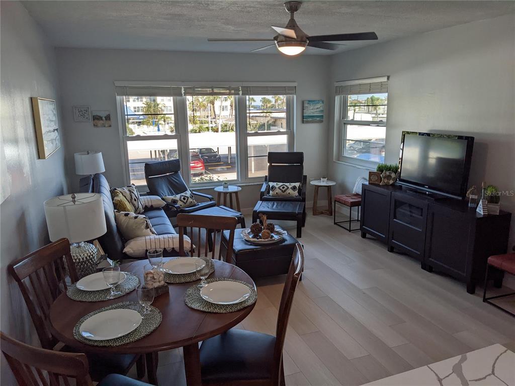 A living and dining area features light wood floors, a ceiling fan, and large windows — 3806 GULF OF MEXICO DRIVE UNIT C208, LONGBOAT KEY, FL