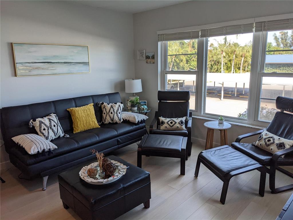 A living room features a black sofa, two matching armchairs with ottomans, and light flooring — 3806 GULF OF MEXICO DRIVE UNIT C208, LONGBOAT KEY, FL