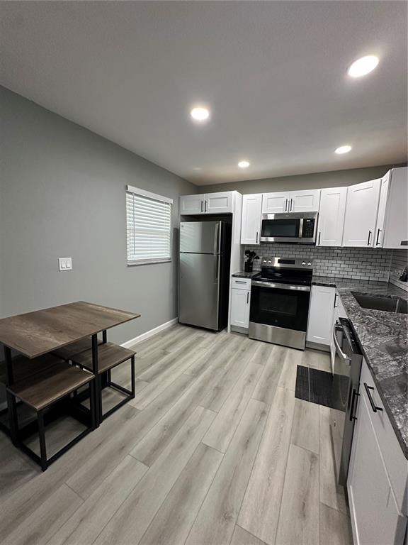 This kitchen features white cabinets, stainless steel appliances, grey countertops, and a small dining table — 460 E BASE AVENUE UNIT 129, VENICE, FL