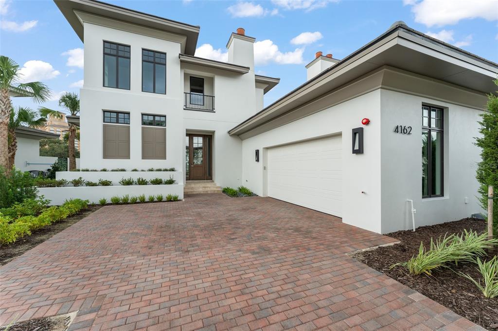 A modern two-story house with white stucco walls, a brick driveway, and a two-car garage — 4162 GRANDE BRICK LOOP UNIT 27, ORLANDO, FL