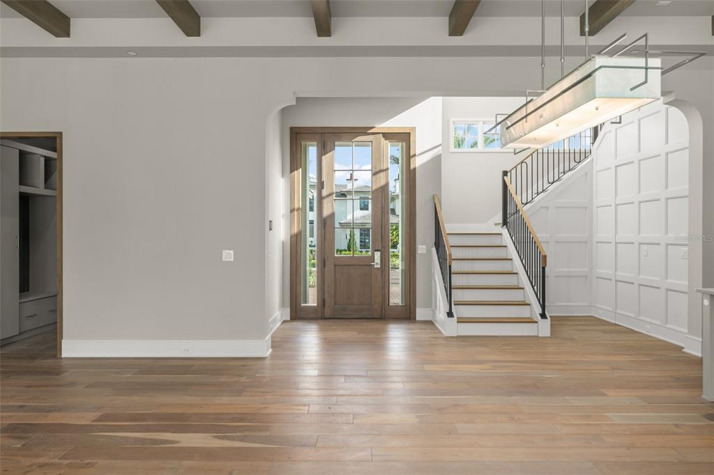 A bright entryway features light wood floors, a wooden front door, and a white staircase — 4162 GRANDE BRICK LOOP UNIT 27, ORLANDO, FL