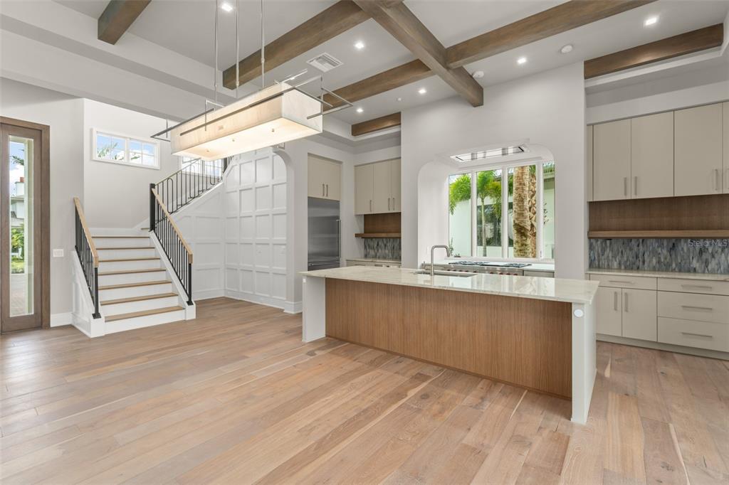 A modern kitchen with a large island, light wood flooring, and a staircase with railing — 4162 GRANDE BRICK LOOP UNIT 27, ORLANDO, FL