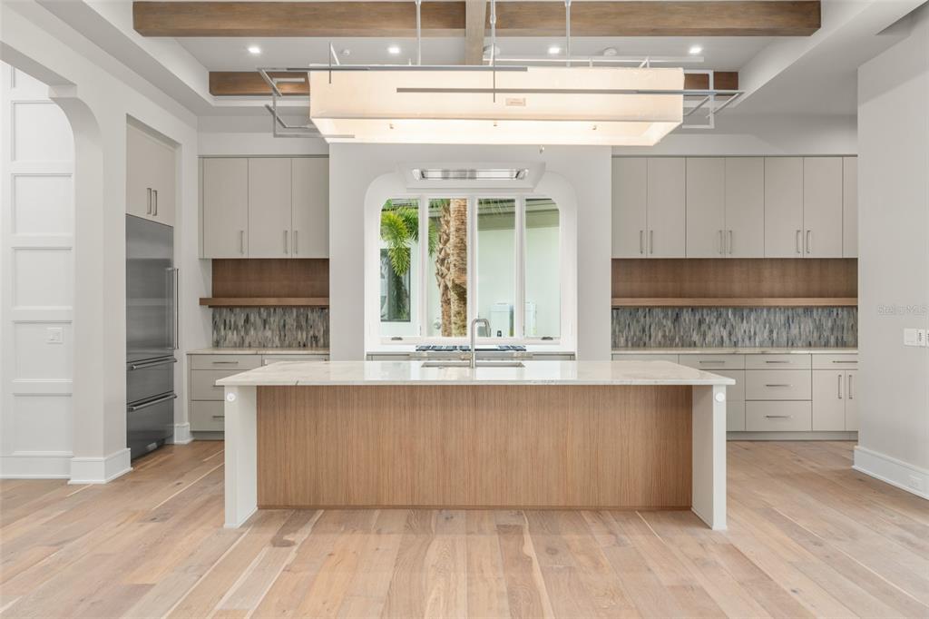 A modern kitchen features a large center island, light wood cabinetry, and a rectangular pendant light — 4162 GRANDE BRICK LOOP UNIT 27, ORLANDO, FL